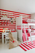 White bunk beds against red and white striped wall with matching rug in children's bedroom
