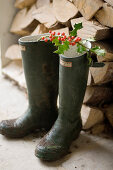 Twig of red berries laid across pair of Wellington boots