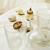 Drinking glasses and various containers made from shells on white tablecloth