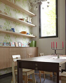 Dining table with chairs in front of open shelving and a sideboard in a wall niche