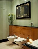 Wall-hung bidet and toilet on half-height wood-panelled wall in bathroom