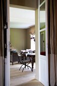 Blick durch offene Flügeltür in einen Wohnraum mit Frühstückstisch und Sofagarnitur