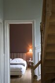 View into bedroom from stairwell with wooden staircase