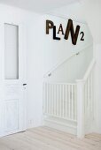 White staircase with safety gate and large letters on wall