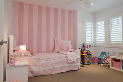 Romantisches Mädchenzimmer in Rosa und Weiß - Vintage Bett vor gestreifter Tapete in Rosa an Wand