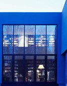 Zeitgenössisches Wohnhaus mit Glasfassade und Blick durch Fenster auf Bücherregale