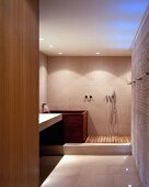 Purist ensuite bathroom with wall-mounted fittings on matte stone tiles, wooden bathtub and shower area with wooden slatted floor