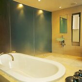 Bathtub in spacious, minimalist bathroom with glass partition