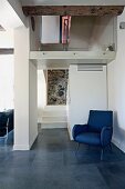 Blauer Sessel im Retrostil in modernem Wohnraum mit offenem Treppenhaus