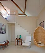 Hängesessel aus Korbgeflecht in modernem Wohnraum mit Treppenaufgang