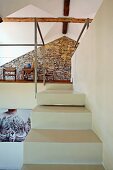 Treppenaufgang aus weissen Stufen und Blick auf Galerie mit Natursteinwand