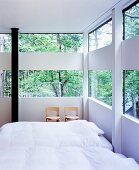Schlafzimmer in einem Haus aus Glas- und Holzkonstruktion im Wald