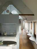Open-plan kitchen in attic and curved window sills along long wall of windows
