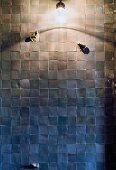 Wandlampe an gefliester Wand im Duschbereich