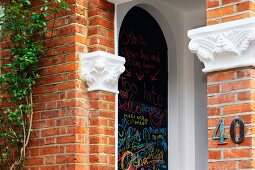 Corner of brick house with stucco elements and graffiti on black wall surface