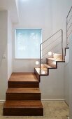 Modern stairwell with square spiral wooden staircase and stainless steel balustrade