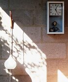 Retro wall clock and pendant light on unrendered concrete block wall