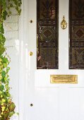 weiße, antike Haustür mit farbigen Bleiglasfenstern und Messing-Briefschlitz