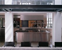 A stainless steel designer kitchen with an island cooker and an industrial atmosphere