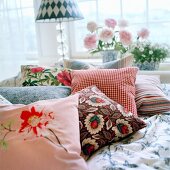 Several scatter cushions on patterned bed linen