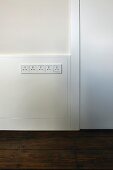 Half-height, white wood panelling and integrated row of plug sockets