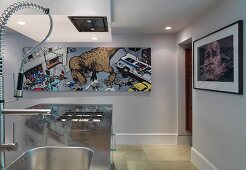 Stainless steel kitchen island and picture with comic motif on wall