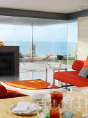 Designer living room with glass walls with a view of a terrace and the ocean beyond