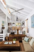 Antique coffee table, simple sofa and gallery in open-plan interior of house with white wooden ceiling