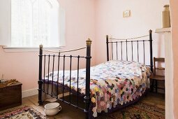 Single bed with antique metal frame in traditional bedroom