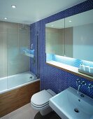 Mirrored cabinet in niche of wall with blue mosaic tiles in modern bathroom