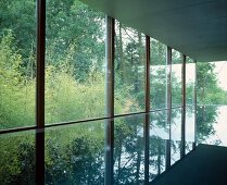 Pool mit spiegelnder Wasseroberfläche im Haus mit Glasfassade
