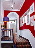 Stairs & landing with red and white walls & gallery of pictures