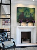 Modern art and bouquets above burning fire in elegant living room