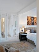 Modern fitted wardrobe with mirrored door in comfortable bedroom
