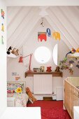 White cabin bedroom for two children with colourful decorations in steeply slanting ceiling structure