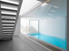 Glass wall in stairwell with view of narrow indoor swimming pool