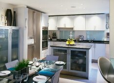 Festive, set table and central kitchen island in modern, white kitchen-dining room