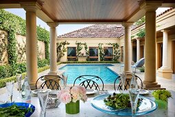 Gedeckter Tisch auf Terrasse mit Säulen und Pool im herrschaftlichen Anwesen