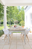 Rustikaler Tisch mit Schalenstühlen auf überdachter Terrasse im Kolonialstil und Gartenblick