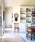 White kitchen dresser against partition in open-plan dining room of country house