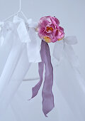 Fabric rose and white ribbons tied in bows on frame