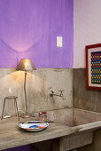 Rustic sink and concrete counter in kitchen with purple wall