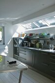 Kitchen counter with grey cupboard doors below skylight in designer kitchen