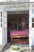 Weiß lackiertes Holz in historischem Landhaus - Blick von Terrasse durch zweiflügelige Tür auf weiss-rot karierterte Bettdecke