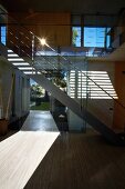 Patterns of light and shade in open-plan stairwell of contemporary house with modern, metal staircase