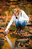 Woman next to stream in autumnal forest