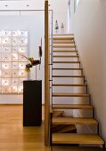 Staircase with wooden treads in open-plan foyer and objet d'art on pedestal and mounted on wall