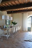 Dining area with white shell chairs on old terracotta floor in renovated country house