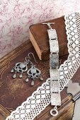 Silver bracelet with floral pattern and drop earrings on old leather bound books