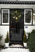 Front door of English country house with Advent wreath and potted conifers decorated for Christmas